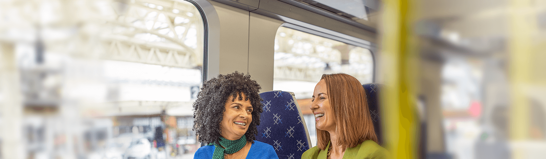 Two females smiling at each other while travelling on a ScotRail train
