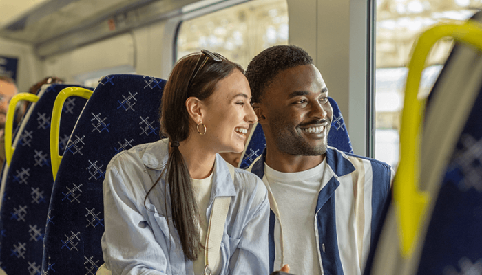 Male and female smiling while looking out the window on a ScotRail train