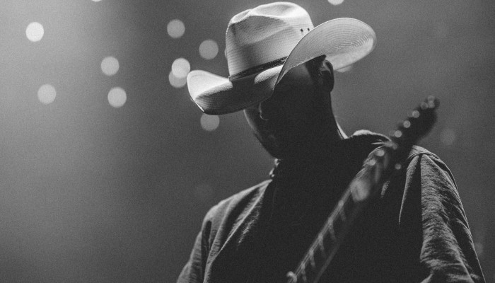 Person wearing a white cowboy hat playing on a lit stage
