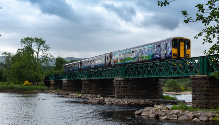 A ScotRail train with Highland Explorer carriages travelling over a viaduct between Crianlarich and Oban.