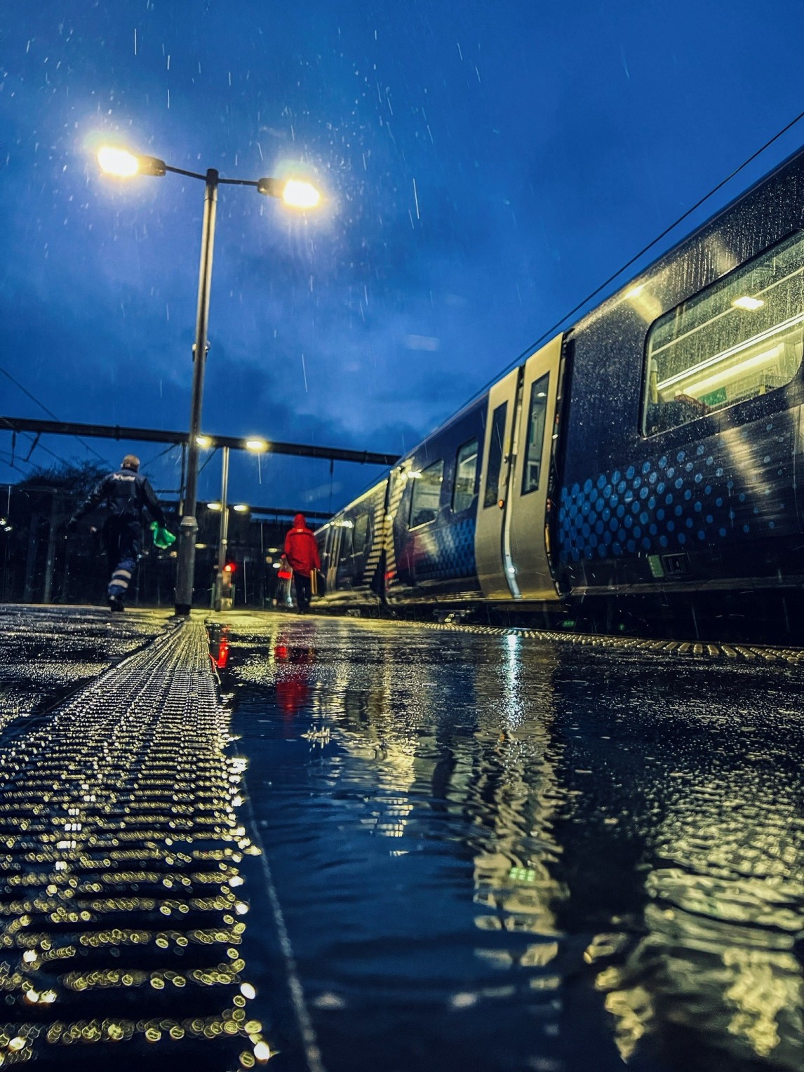 A low angle shot of people boarding a ScotRail train on a rainy day.