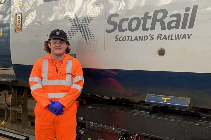 Robbie, engineering apprentice standing infront of a ScotRail train