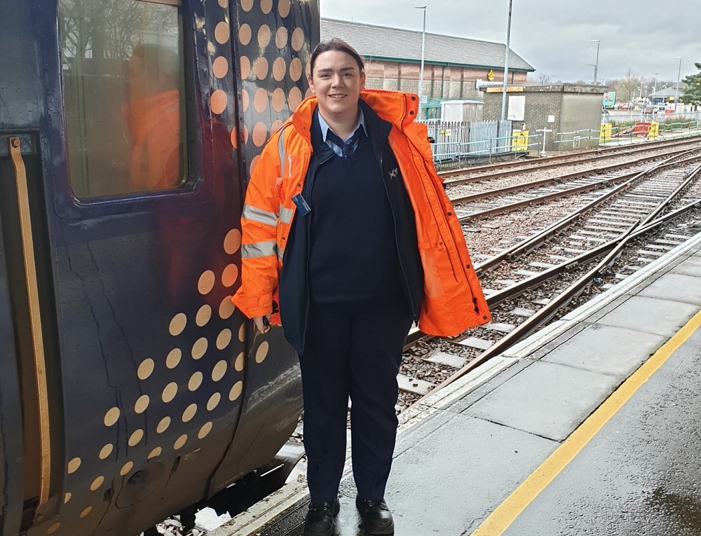 Fiona Hynd-Morrison, Trainee Driver at Fort William standing on station platform infront of ScotRail train