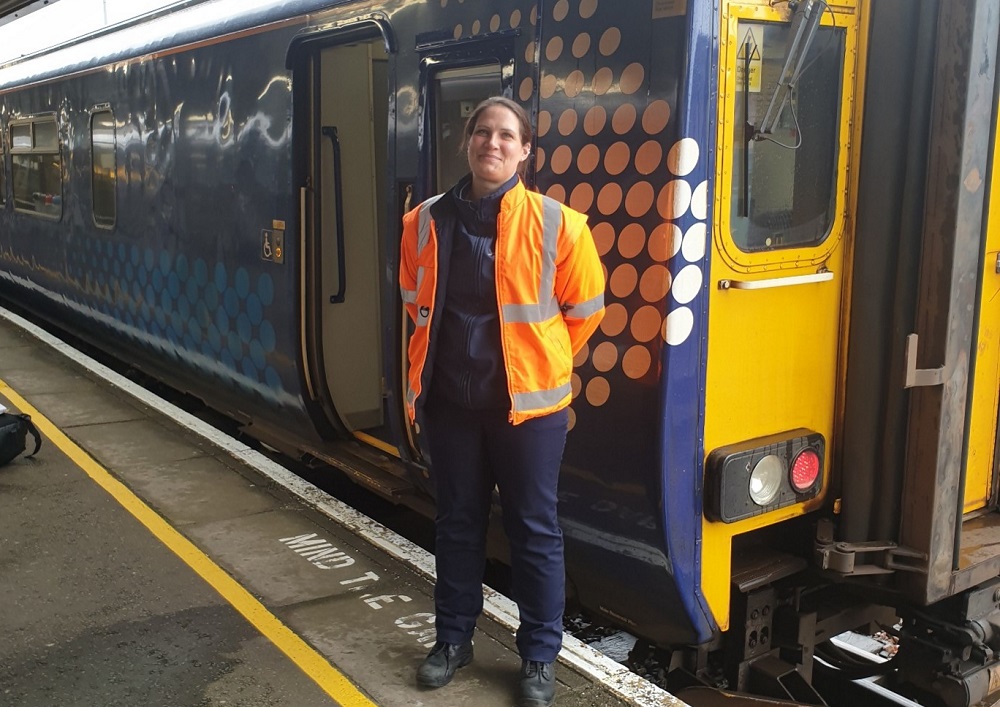 Anne Cameron, Trainee Train Driver at Mallaig, standing on platform infront of ScotRail train