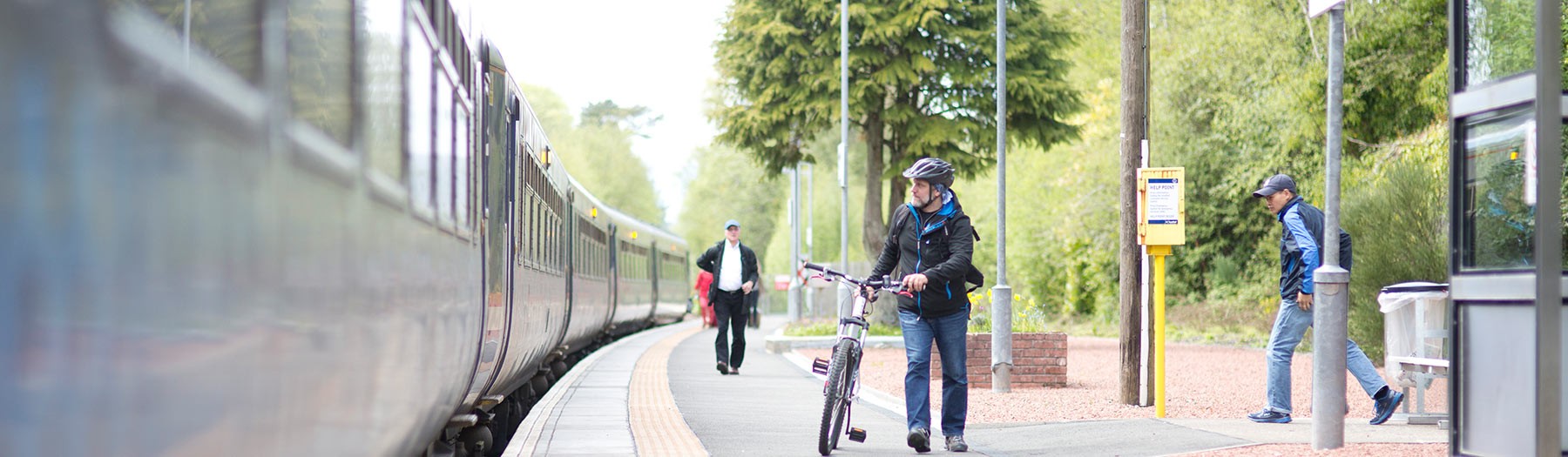 man wheeling bike on station platform
