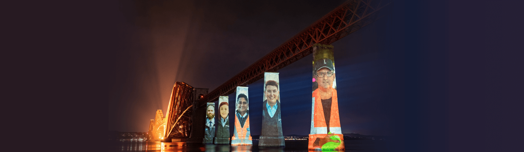 Forth Bridge at night with projections of ScotRail staff