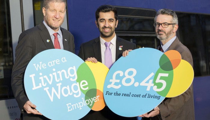 Phil Verster, Managing Director, ScotRail Alliance; Humza Yousaf MSP, Minister for Transport and the Islands; Peter Kelly, Director of the Poverty Alliance holding Living Wage banner in front of a ScotRail train