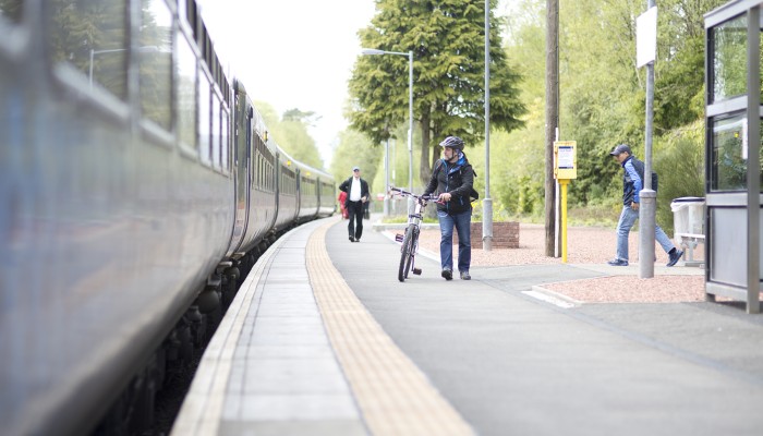 Man wheeling a bike along station platform