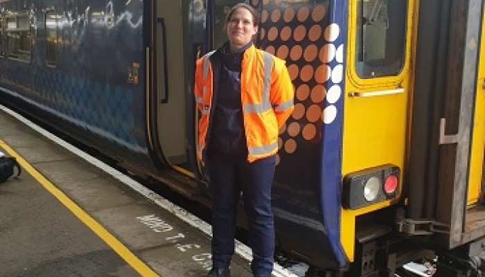 Anne Cameron, trainee driver at Mallaig standing on platform next to ScotRail Train