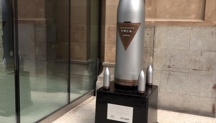 A restored silver First World War artillery shell with plaque on a brown plinth in Aberdeen station