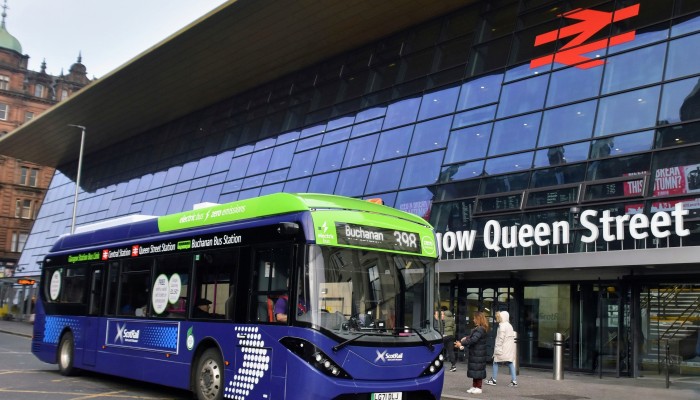 Electric bus in ScotRail branding outside Glasgow Queen Street station.