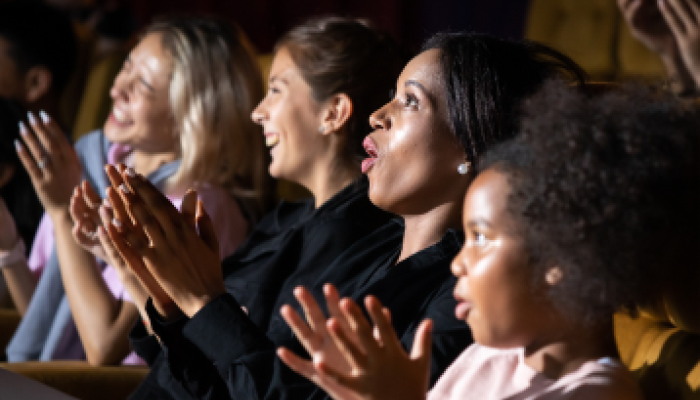 Ladies and young girl clapping and laughing at the theatre