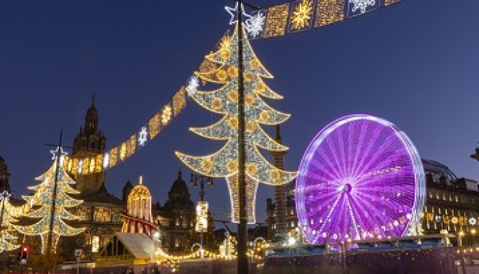 Glasgow's George Square lit up with colourful Christmas lights and decorations with a ferris wheel. 