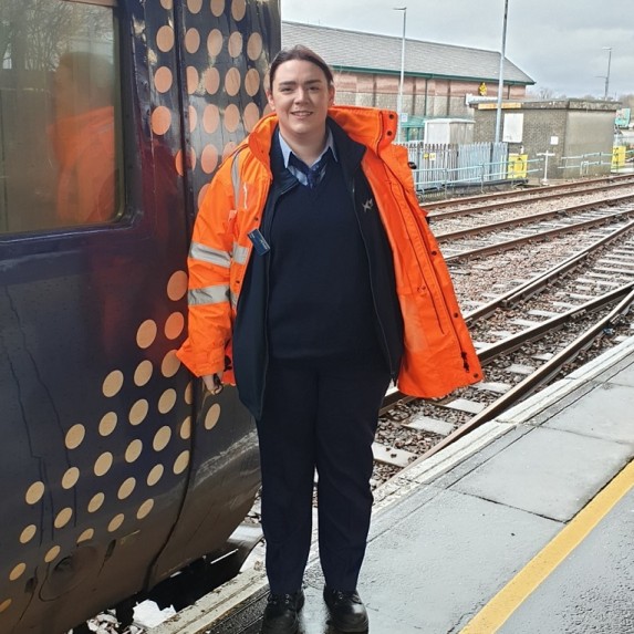 Fiona Hynd-Morrison, Trainee Driver at Fort William standing on station platform infront of ScotRail train