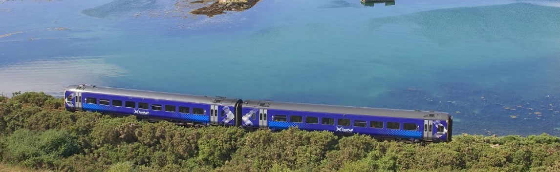 ScotRail train travelling along the Kyle of Lochalsh railway line with water in the background