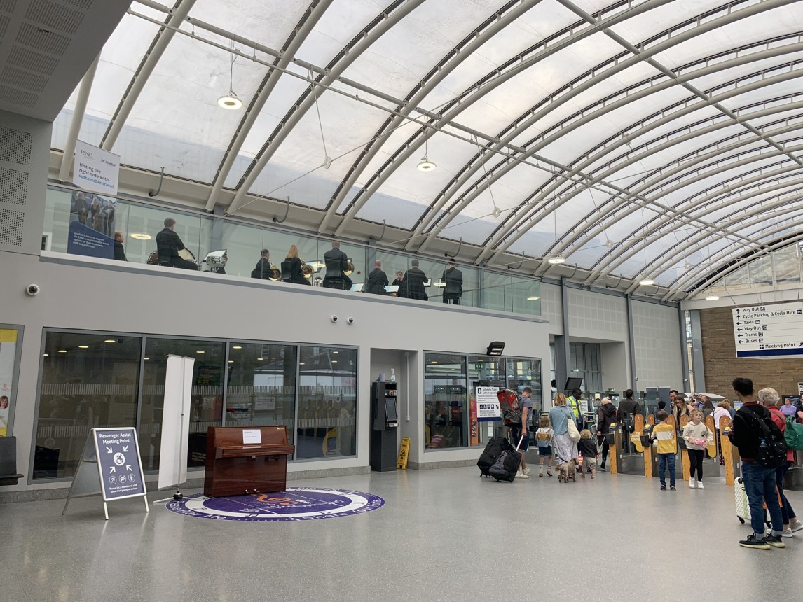 A group of musicians from the RSNO play a concert above Haymarket station concourse.