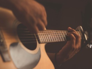 Person playing acoustic guitar with a capo