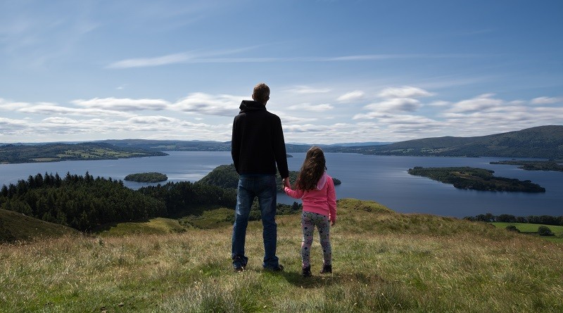 Father and daughter overlooking loch