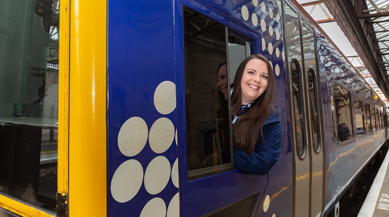 Emma Gill, driver, smiling from train door