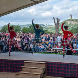 Highland dancers on stage with Wallace Monument the distance